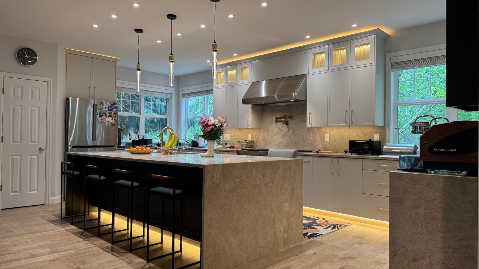 Modern kitchen with quartz waterfall island, brass pendants and LED cove lighting