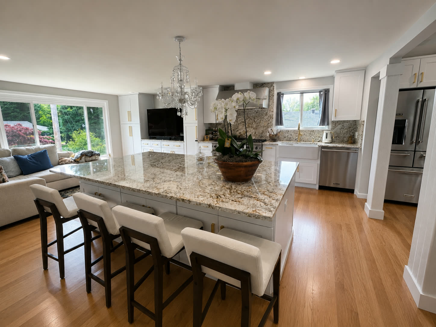 Bright open-concept kitchen with dramatic veined granite island and chandelier
