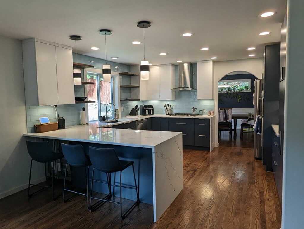 Contemporary U-shaped kitchen with white quartz waterfall peninsula and blue subway backsplash