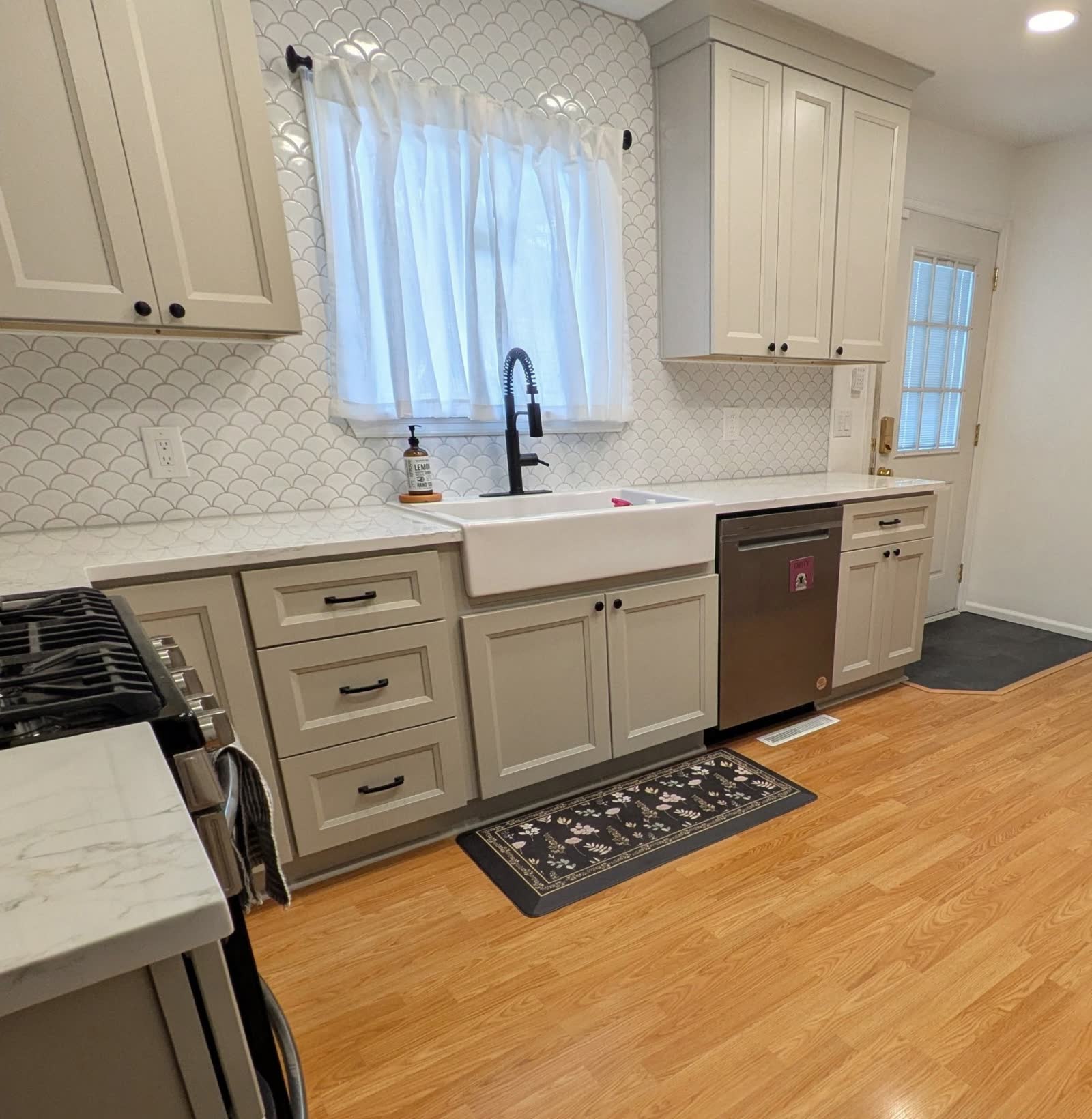 Greige kitchen with white quartz counters, farmhouse sink and fish-scale backsplash