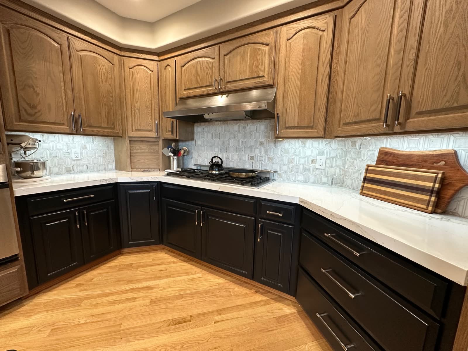 Two-tone kitchen with oak uppers, black lowers, quartz counters and patterned backsplash