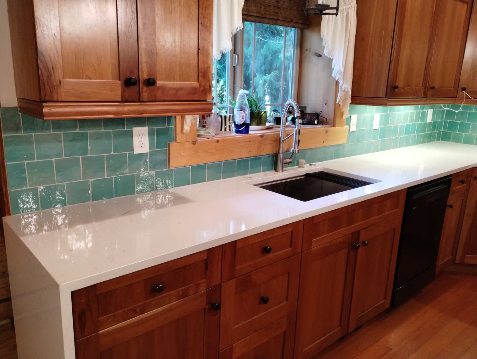 Warm wood kitchen with glossy green subway tile backsplash and white quartz counters
