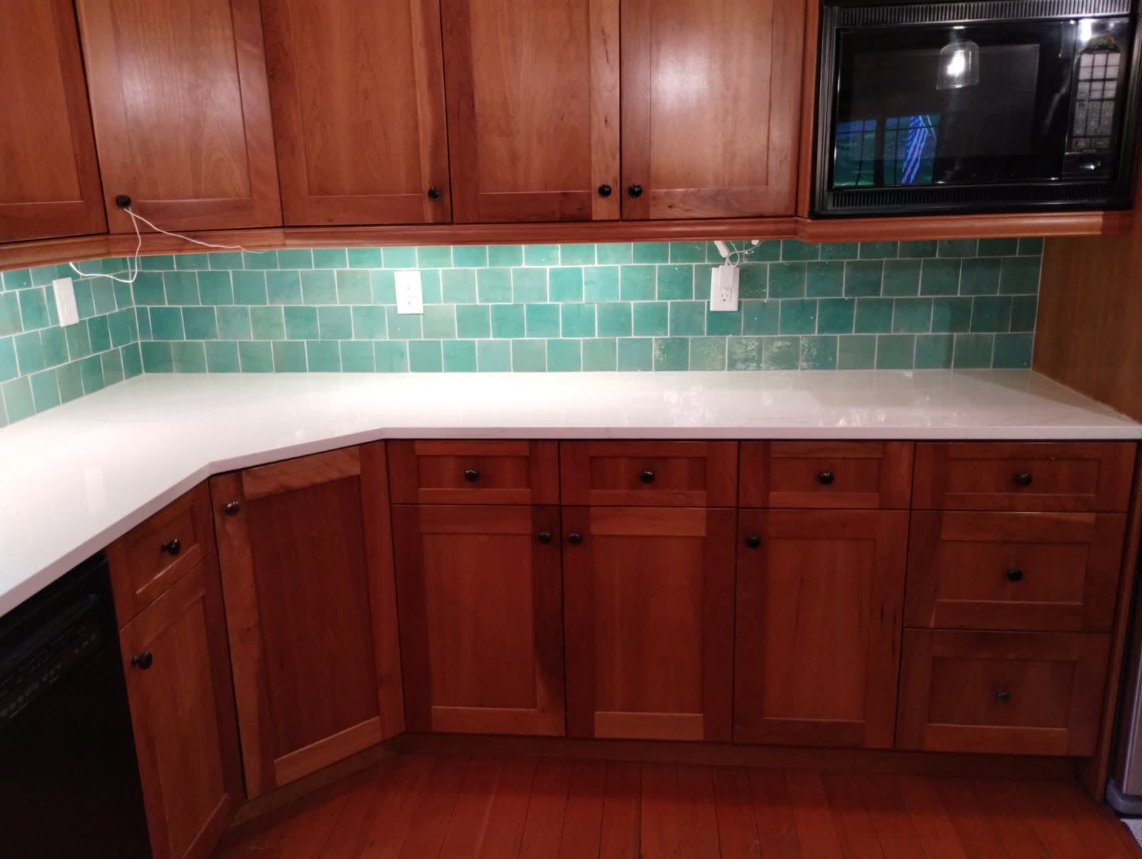 Wood cabinetry and turquoise tile backsplash with bright white quartz surfaces