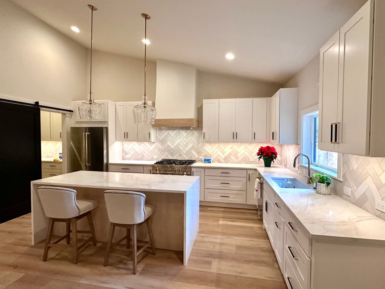 Bright custom kitchen with waterfall island and soft herringbone backsplash.