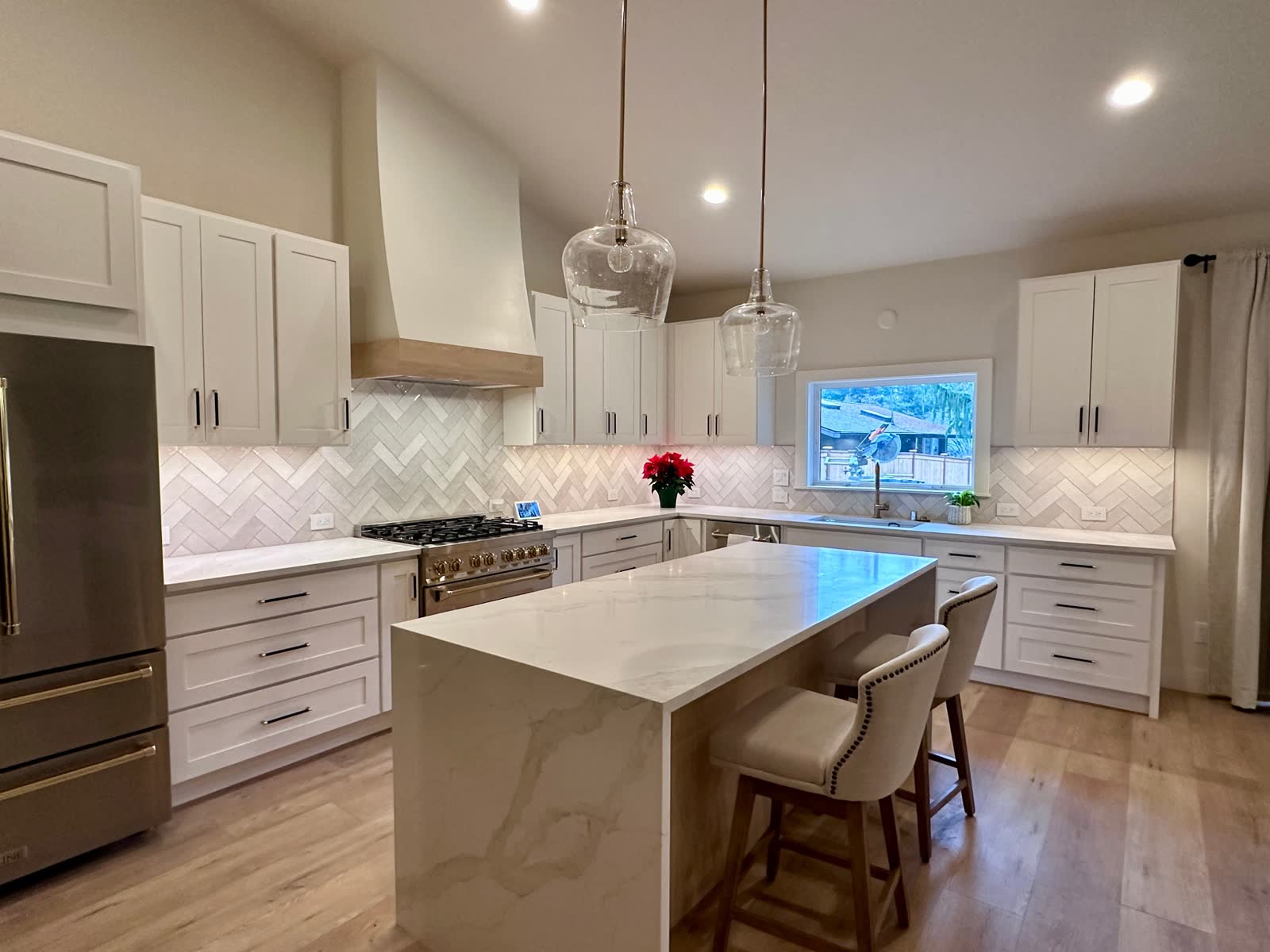 Open-concept kitchen with oversized waterfall quartz island and tall white cabinetry