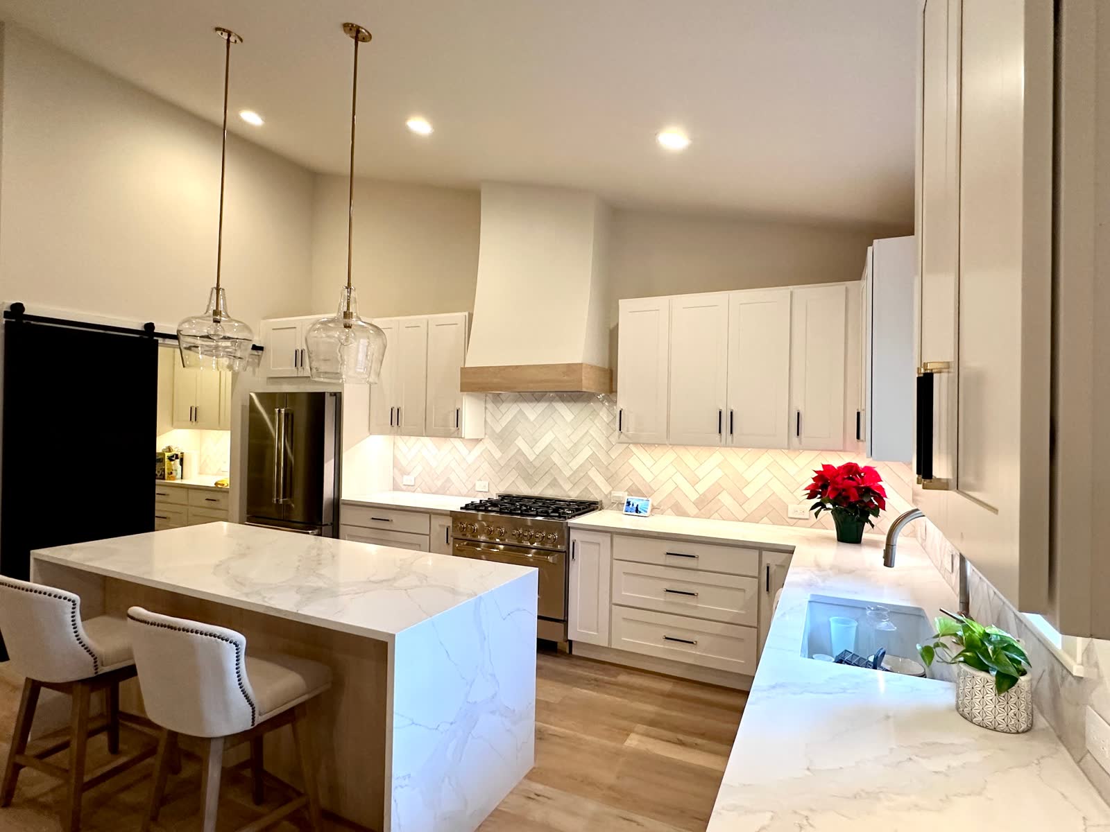 Modern white kitchen with waterfall island, pendant lights and herringbone tile