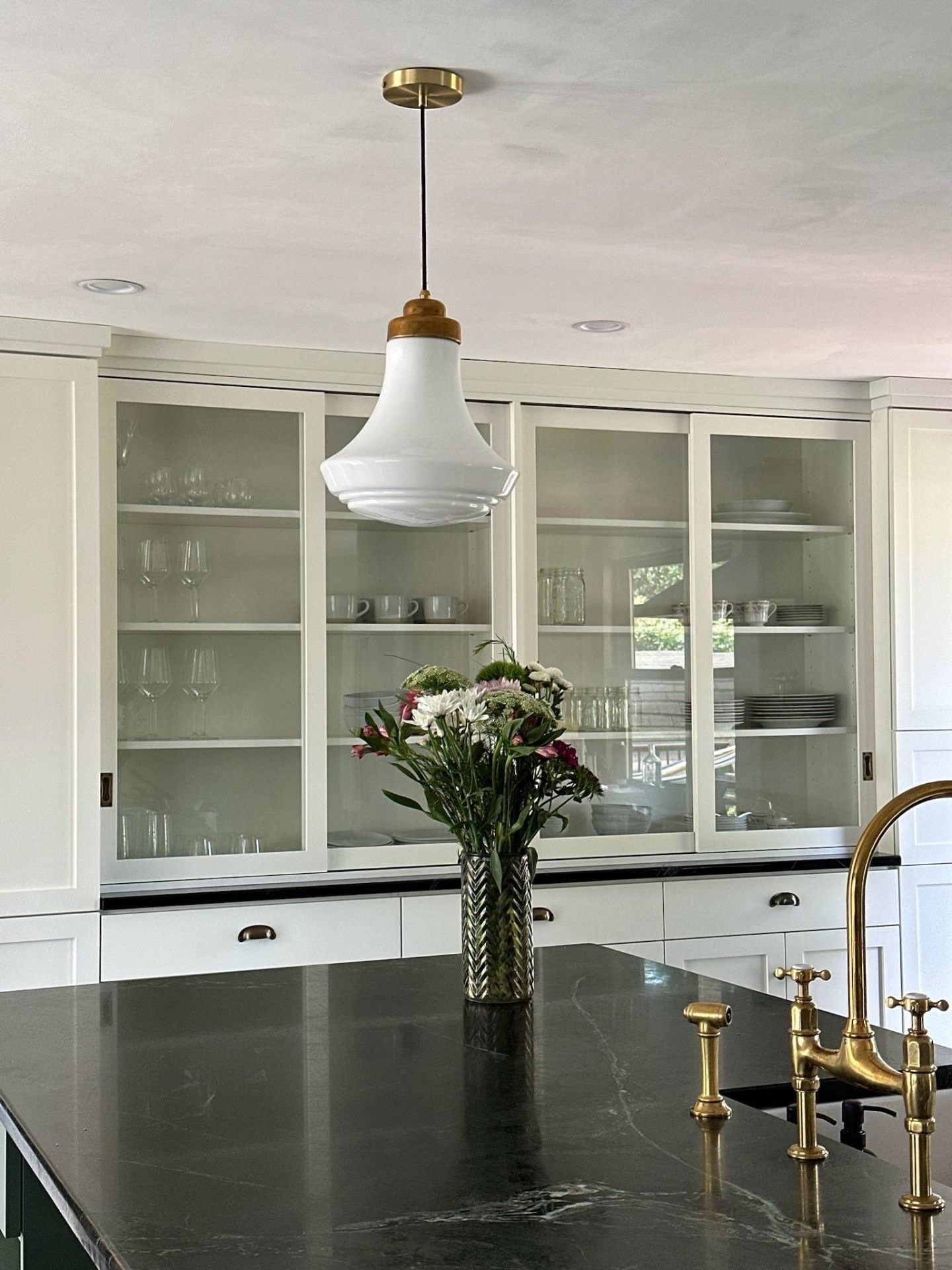 Black stone island with brass faucet and glass-front built-in cabinetry