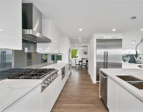 High-gloss white galley kitchen with calacatta quartz counters and stainless hood