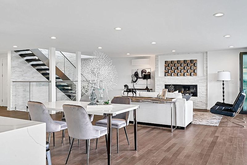 Open-concept living and dining area with stone fireplace wall and floating staircase