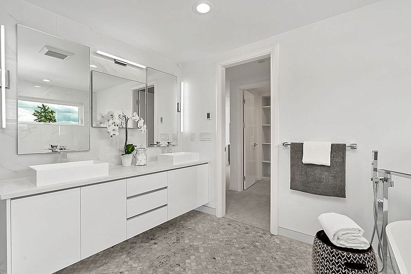 White bathroom with mosaic tile floor and freestanding soaking tub.