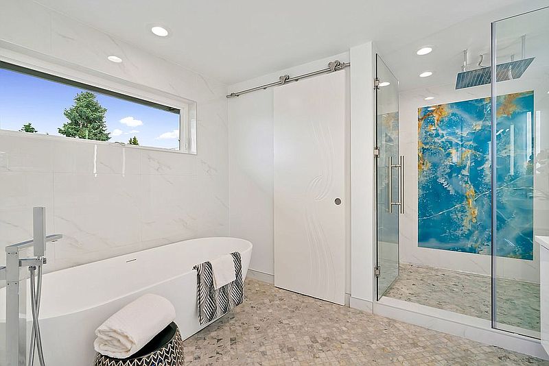 Bright marble bathroom with freestanding tub, glass shower and blue onyx feature wall