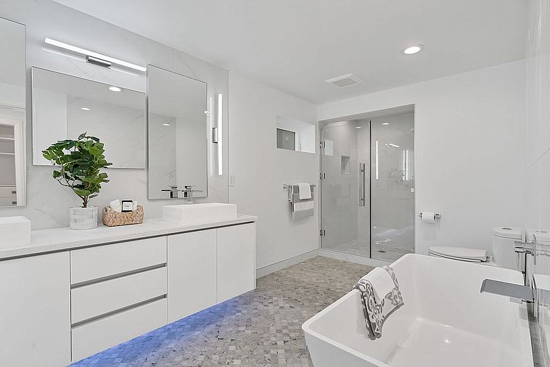 Modern white bathroom with floating vanity, freestanding tub and mosaic tile floor