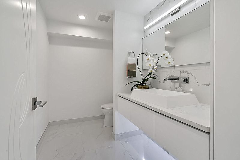Compact powder room with floating vanity, vessel sink and marble accent wall
