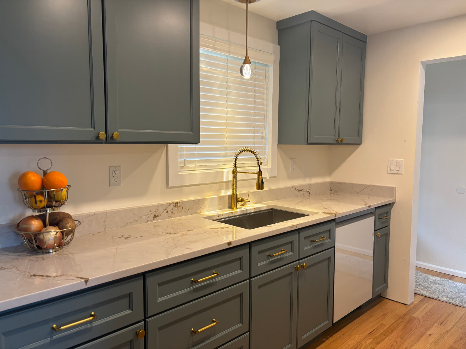 Sage green cabinetry with dramatic gold-veined quartz counter and brass gooseneck faucet