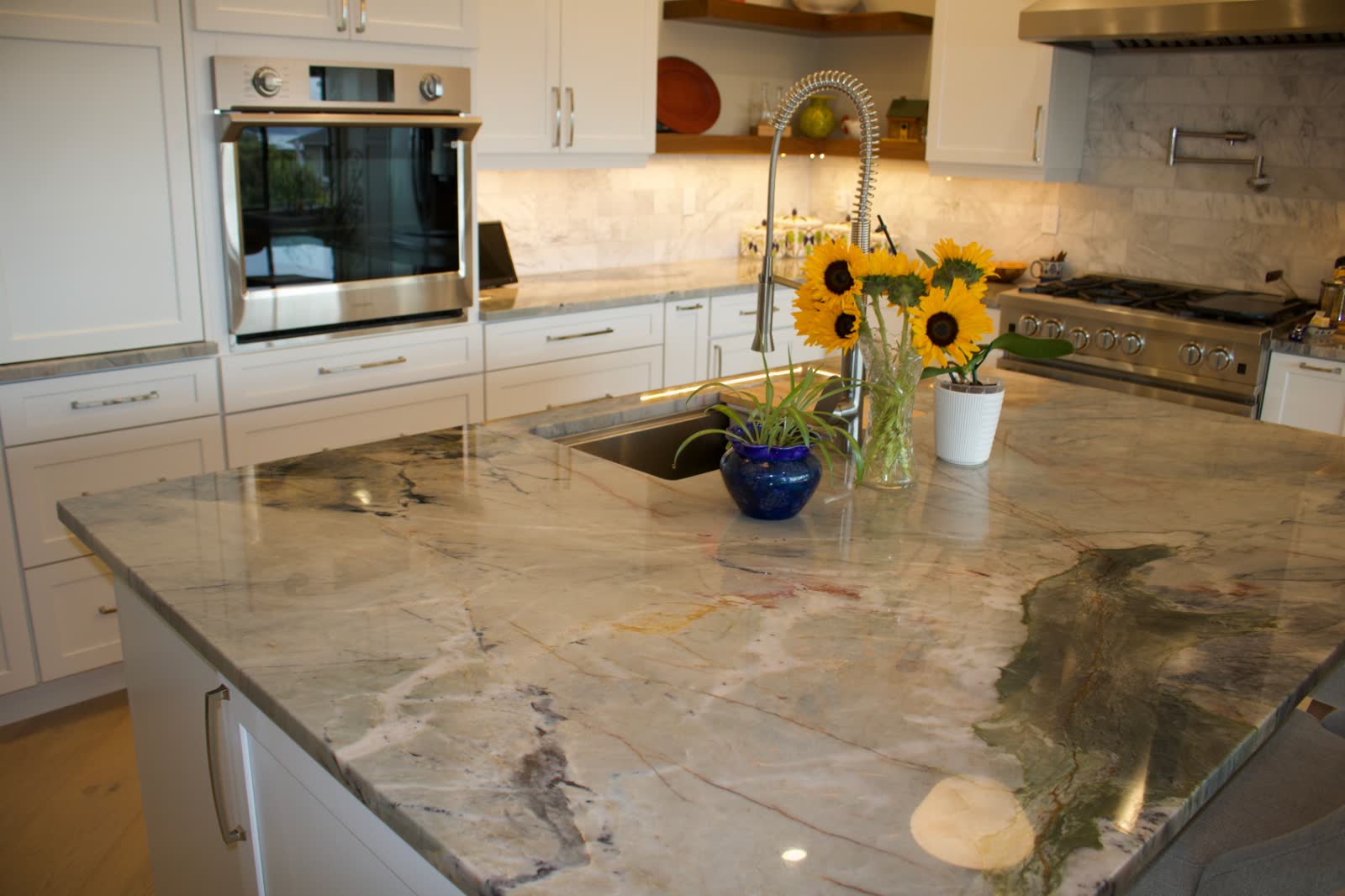 Dramatic quartzite island with blue and green veining, stainless sink and gooseneck faucet