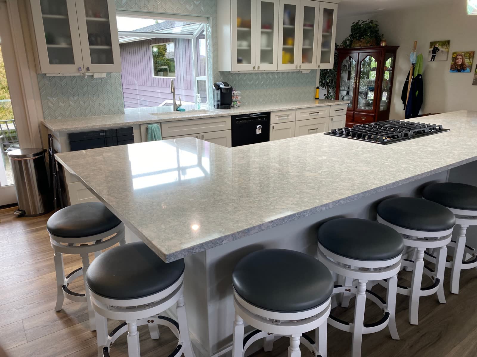 Long quartz island with seating for six and chevron glass tile backsplash