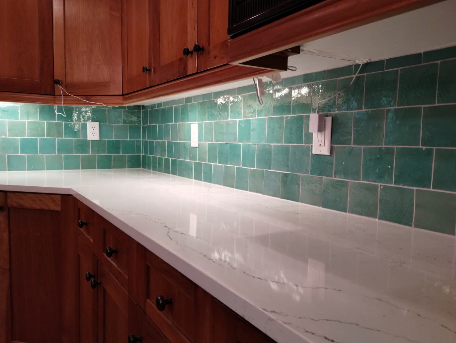 Veined white quartz counter with glossy green square tile backsplash