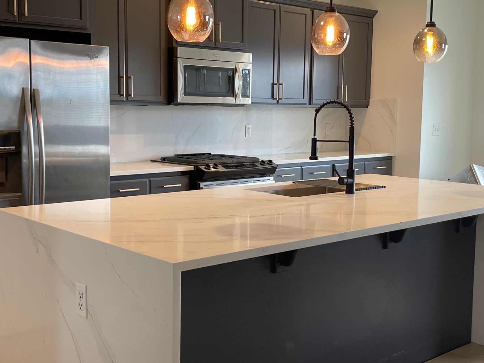 Calacatta quartz peninsula with waterfall edge and seeded-glass pendant lights