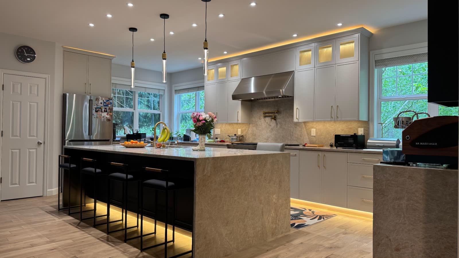 Two-tone kitchen with quartzite island, black display cabinetry and warm LED under-cabinet lighting