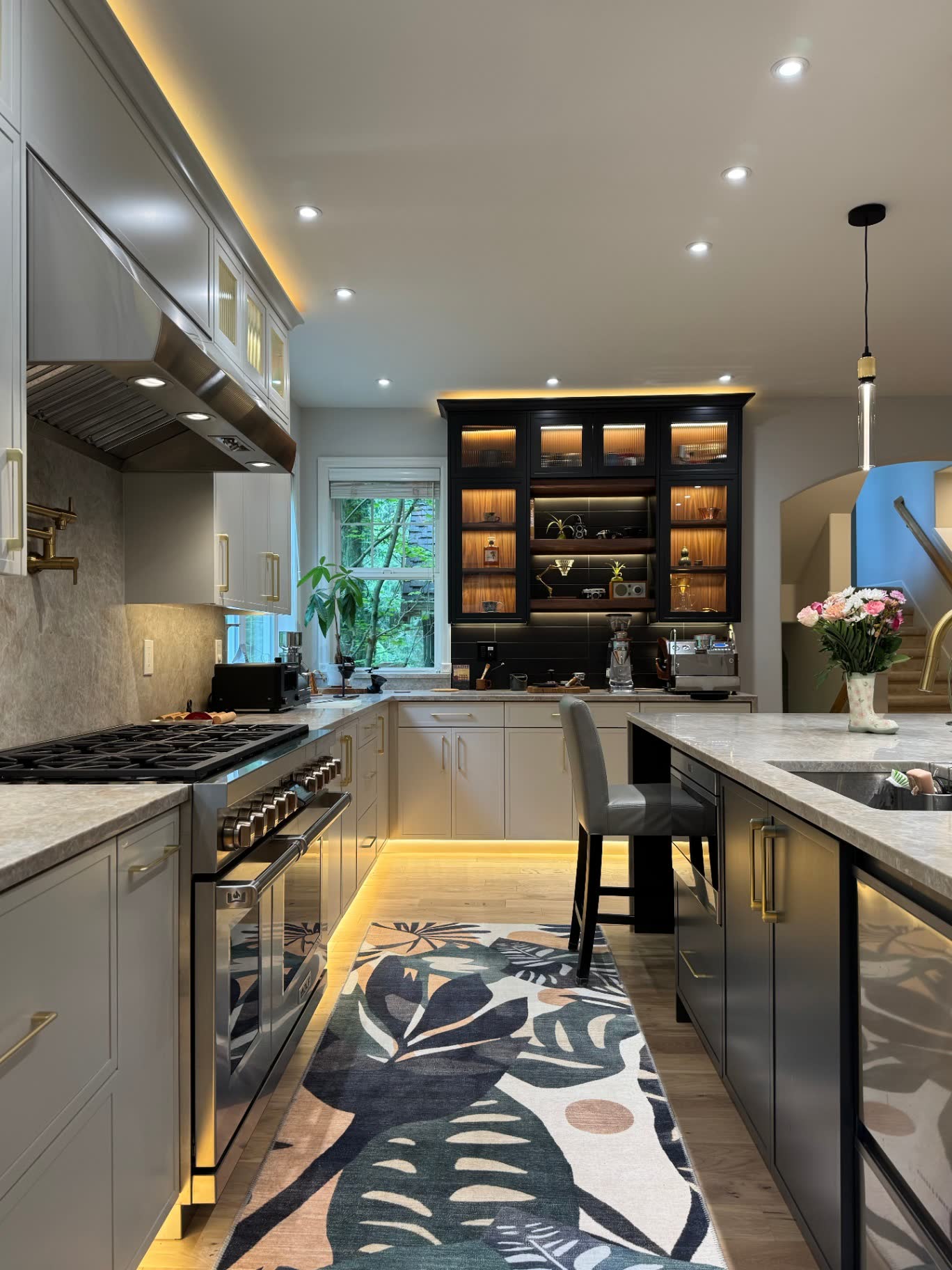 Chef's kitchen with pro range, black display hutch, quartzite counters and integrated LED lighting