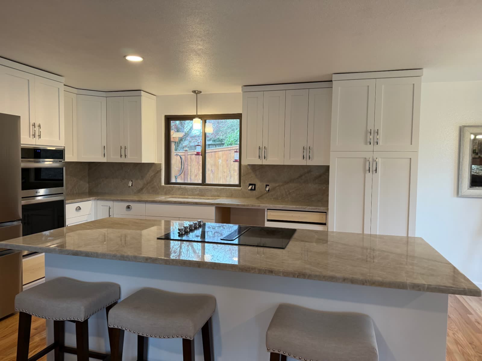 White shaker kitchen with quartzite counters, wall oven and peninsula seating