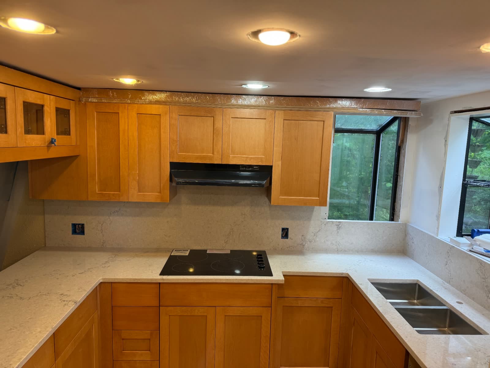 Maple shaker kitchen with quartz counters, cooktop and stainless sink