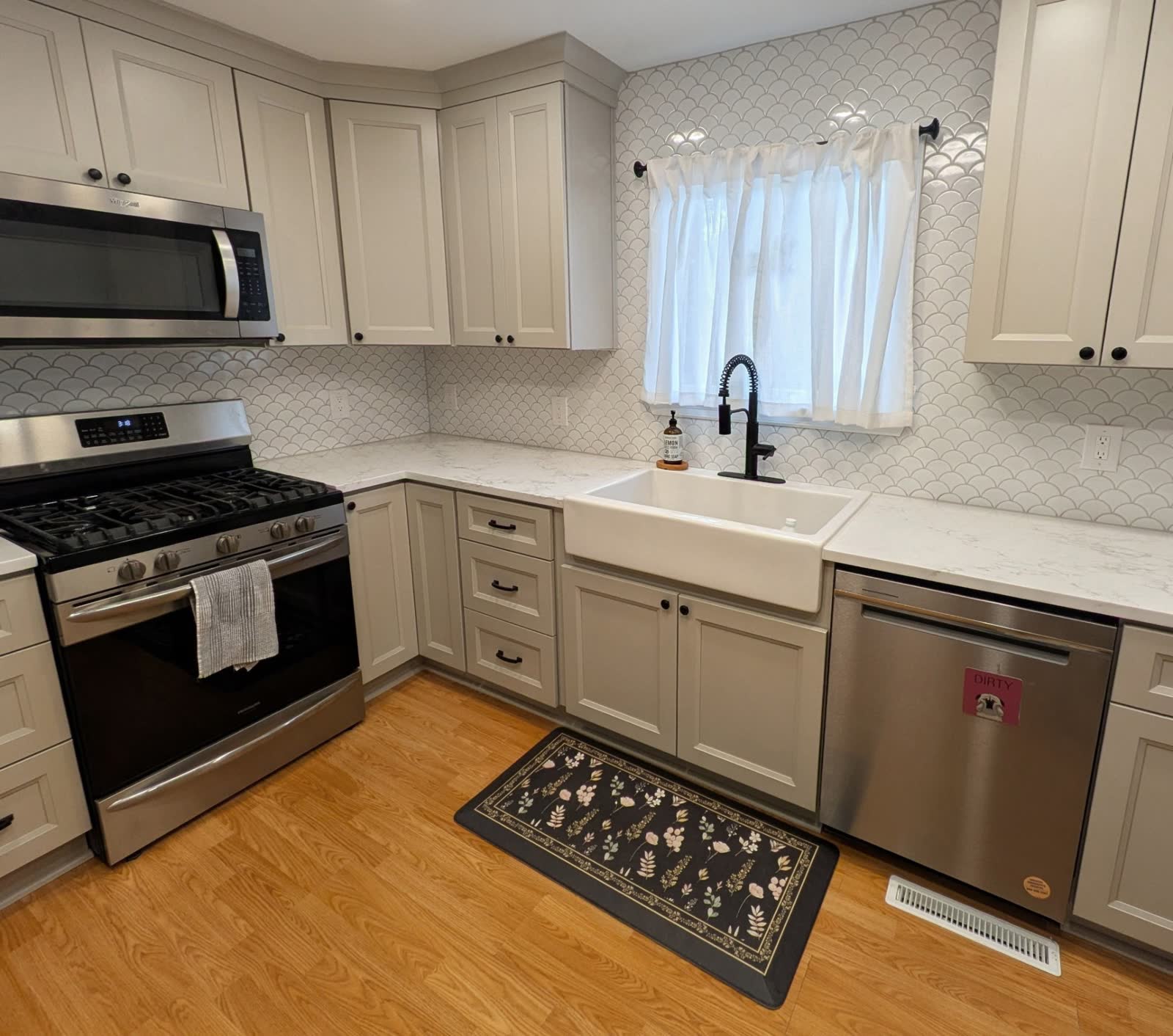 Quartz counter and scalloped tile backsplash with stainless gas range