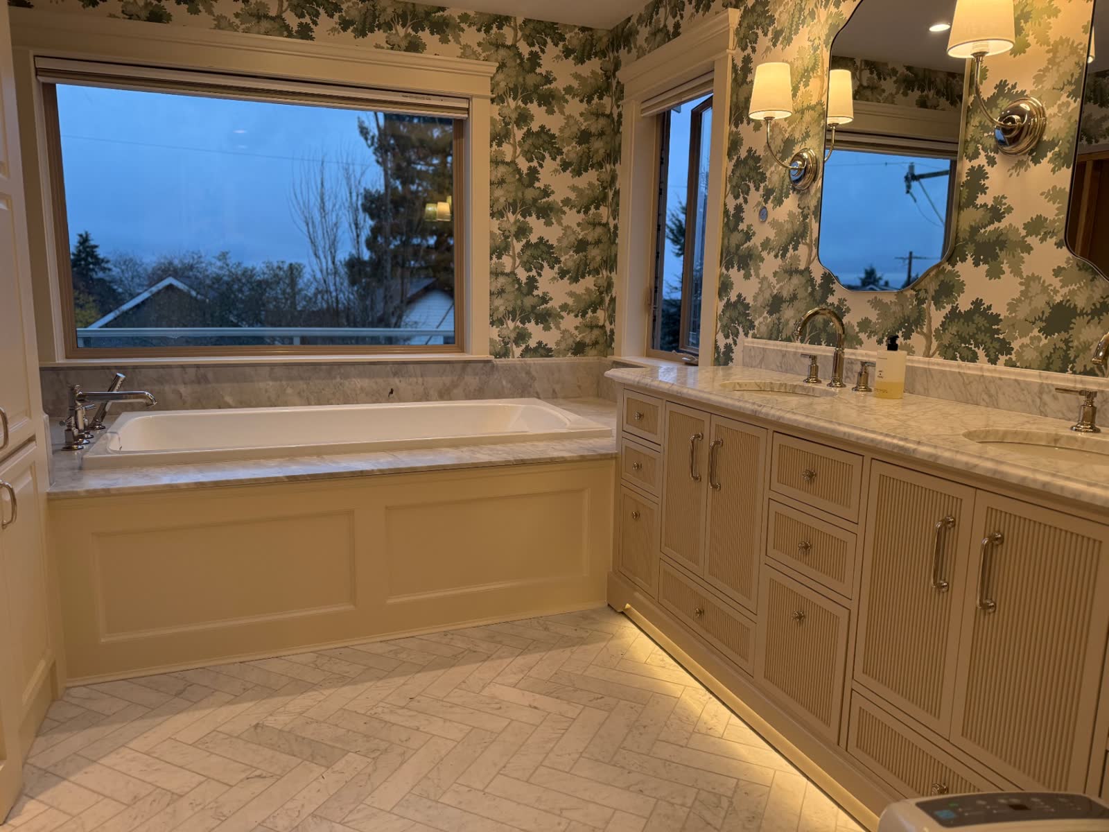 Traditional primary bath with soaking tub and marble herringbone floor.