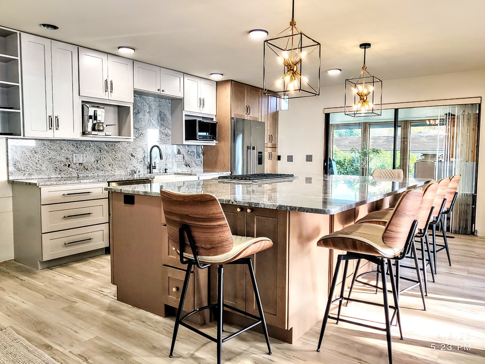 Two-tone kitchen with white perimeter, maple island seating and granite counters