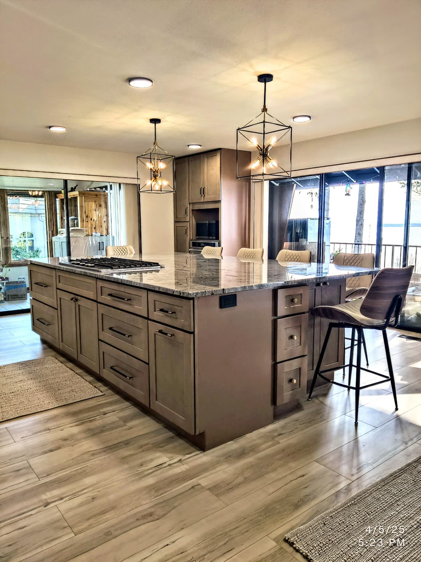 Spacious maple island kitchen with granite counters and lantern pendants opening to deck