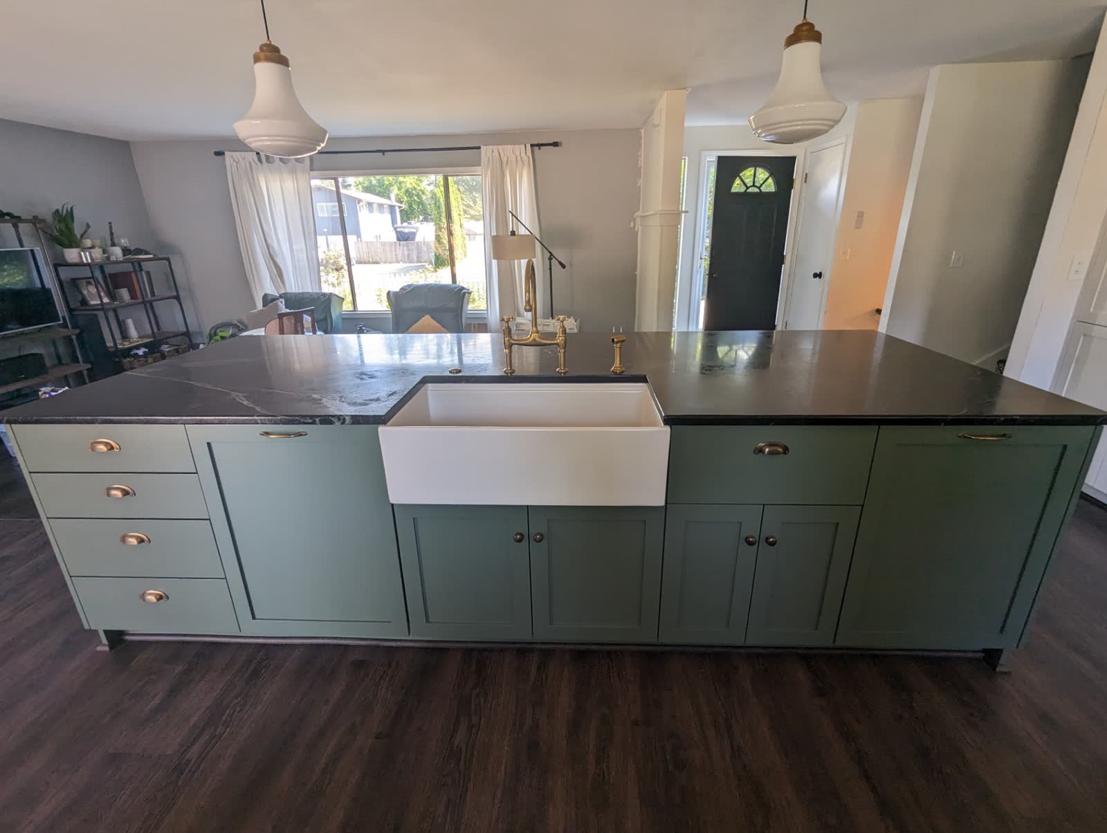 Sage green island with soapstone counter, farmhouse sink and brass bridge faucet